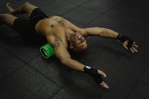 Man using foam roller at gym—illustrating the debate of sports massage vs foam rolling for muscle recovery.