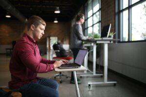 Man sitting at a desk practicing good posture and workspace ergonomics to correct bad posture.